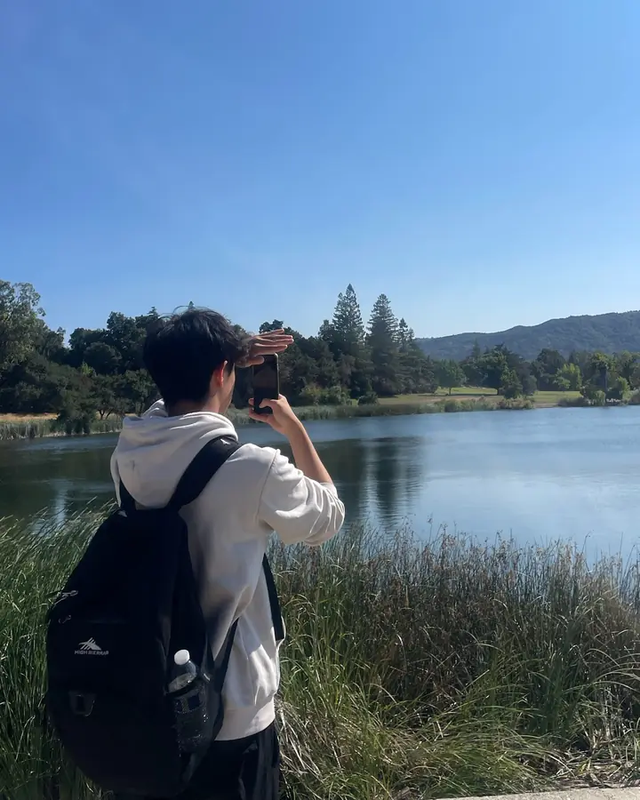 Justin from behind, photographing a lake and the hills beyond it