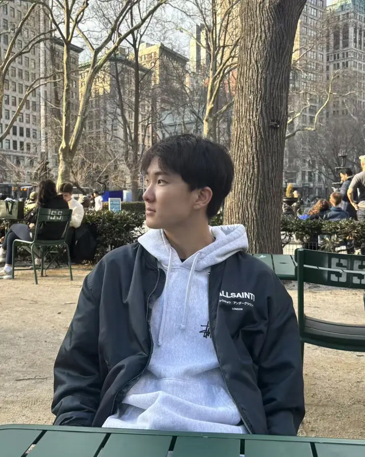 Justin at a table in a city park, looking off to the side